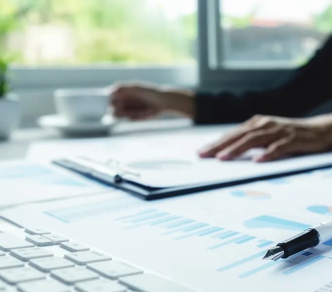 Professional reviewing financial reports beside a laptop