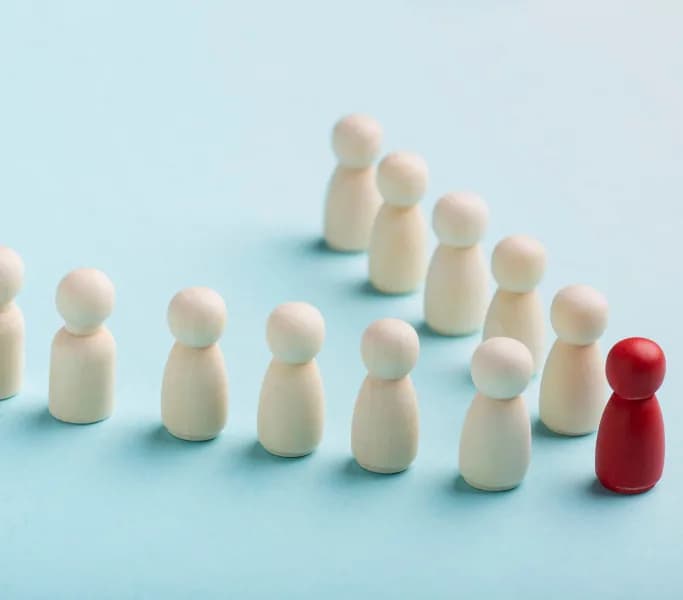 Wooden figures grouped around a red figure representing a team leader