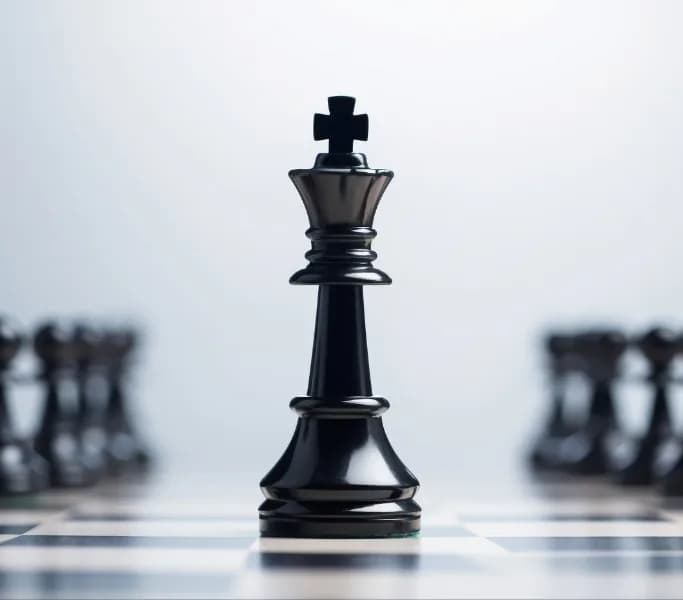 Black chess king in the foreground on a chessboard